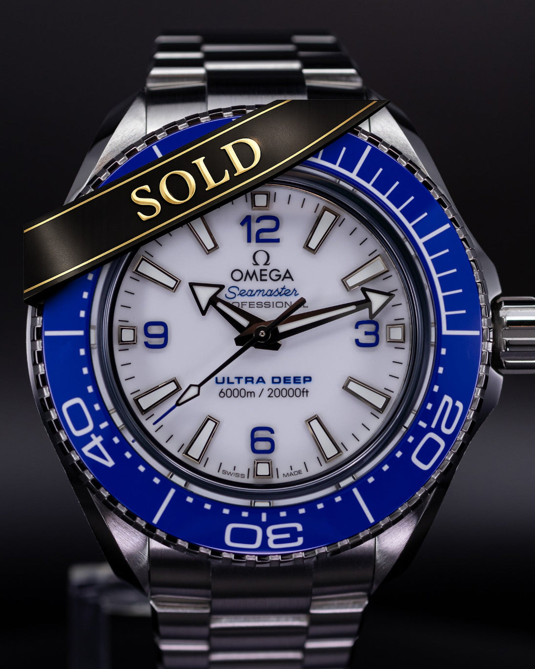 Omega watch with blue bezel and 'SOLD' label on a dark background